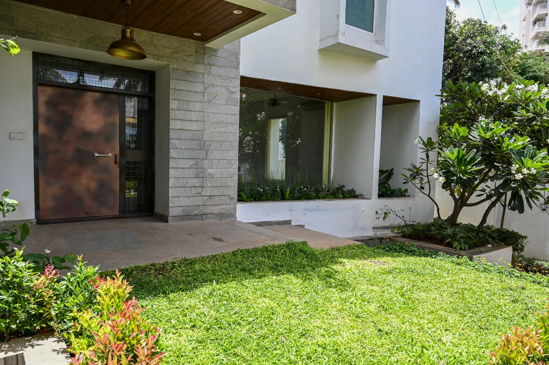 Front entrance with copper door, granite cladding and raised lawn, Prestige Laughing Waters luxury villa for rent, Whitefield, Bangalore