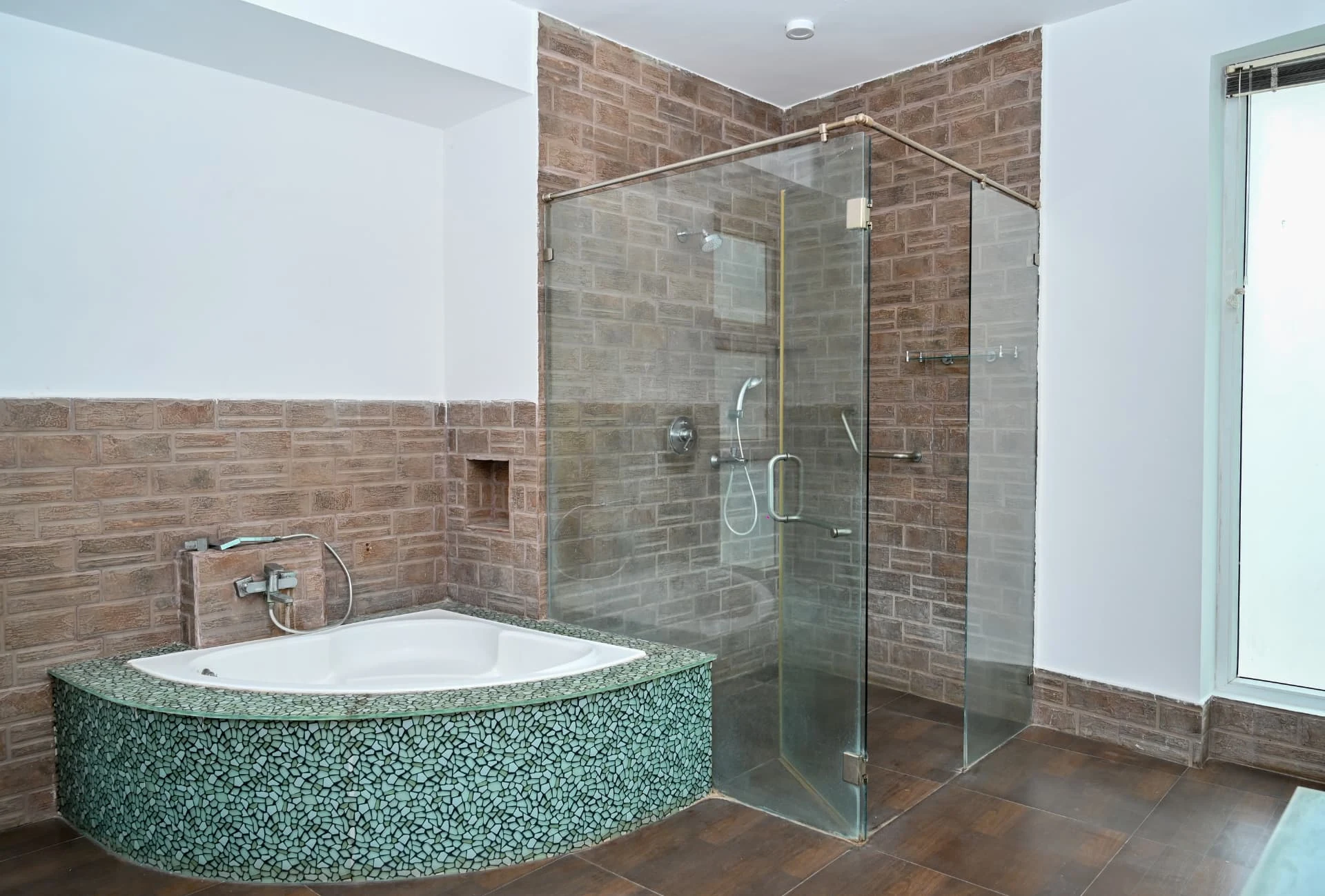 Master bathroom corner bathtub in mosaic tiling beside a glass shower, Prestige Laughing Waters luxury villa for rent, Whitefield, Bangalore
